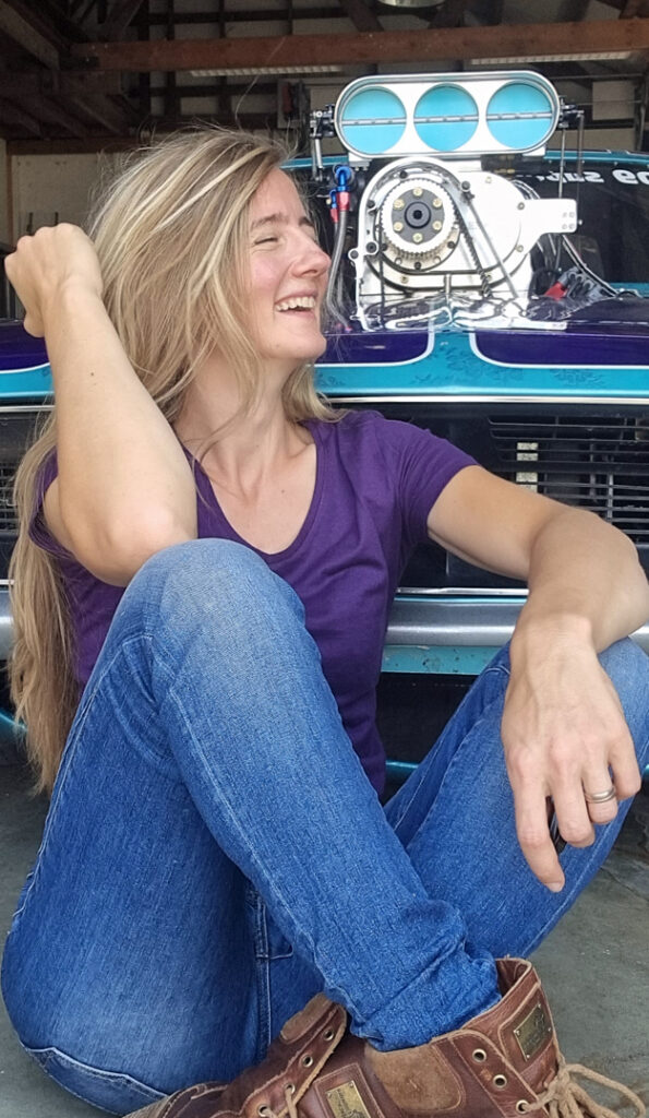 Kirsten van Croonenborgh laughing and sitting in front of dragrace car SuzyQ